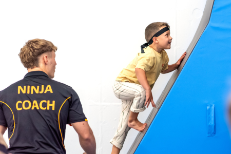 Ninja participant climbing vertical wall