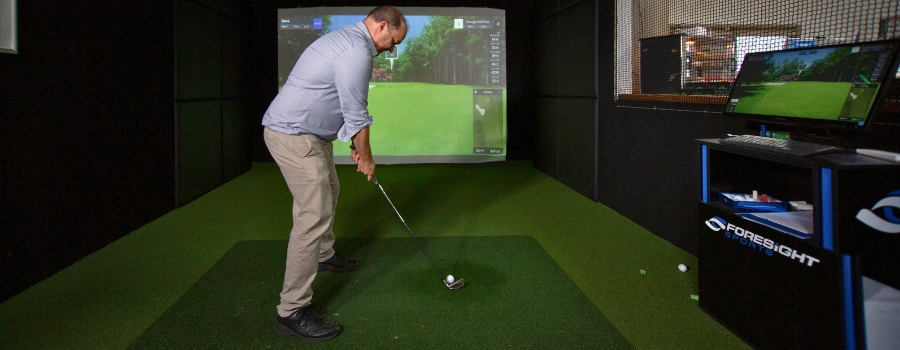 Man about to hit a golf ball while playing golf on the Golf Simulator