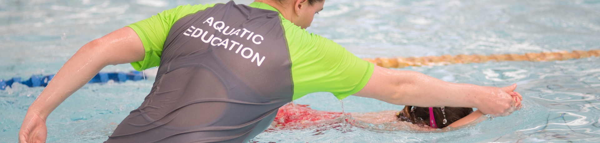 Aquatic educator teaching a child to kick in thein pool