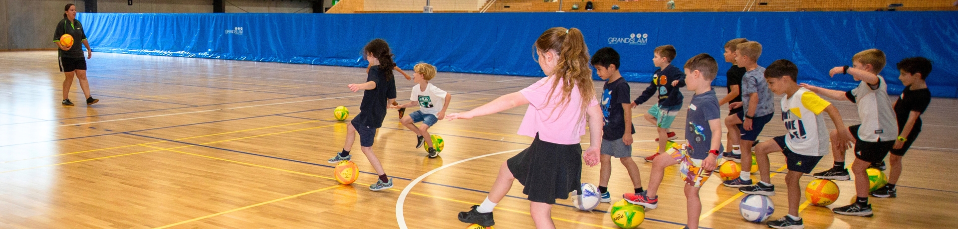 Children learning to play futsal on an indoor court